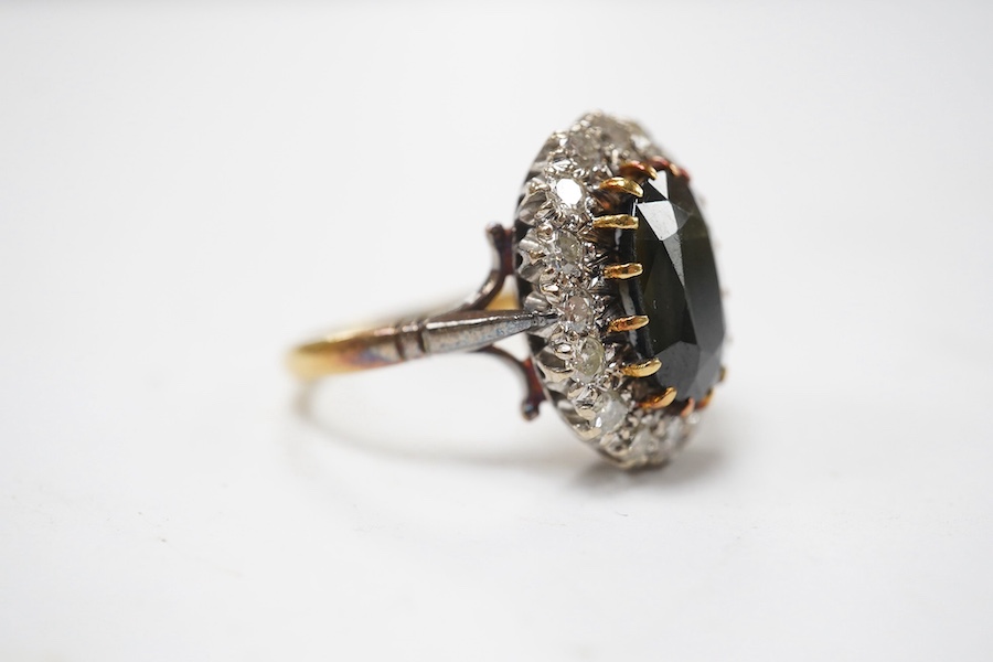 An 18ct, dark green sapphire and diamond set oval cluster ring, size N/O, gross weight 8.6 grams, the Australian sapphire weighing approximately 3.50ct, the total diamond weight approximately 0.64ct. Condition - fair